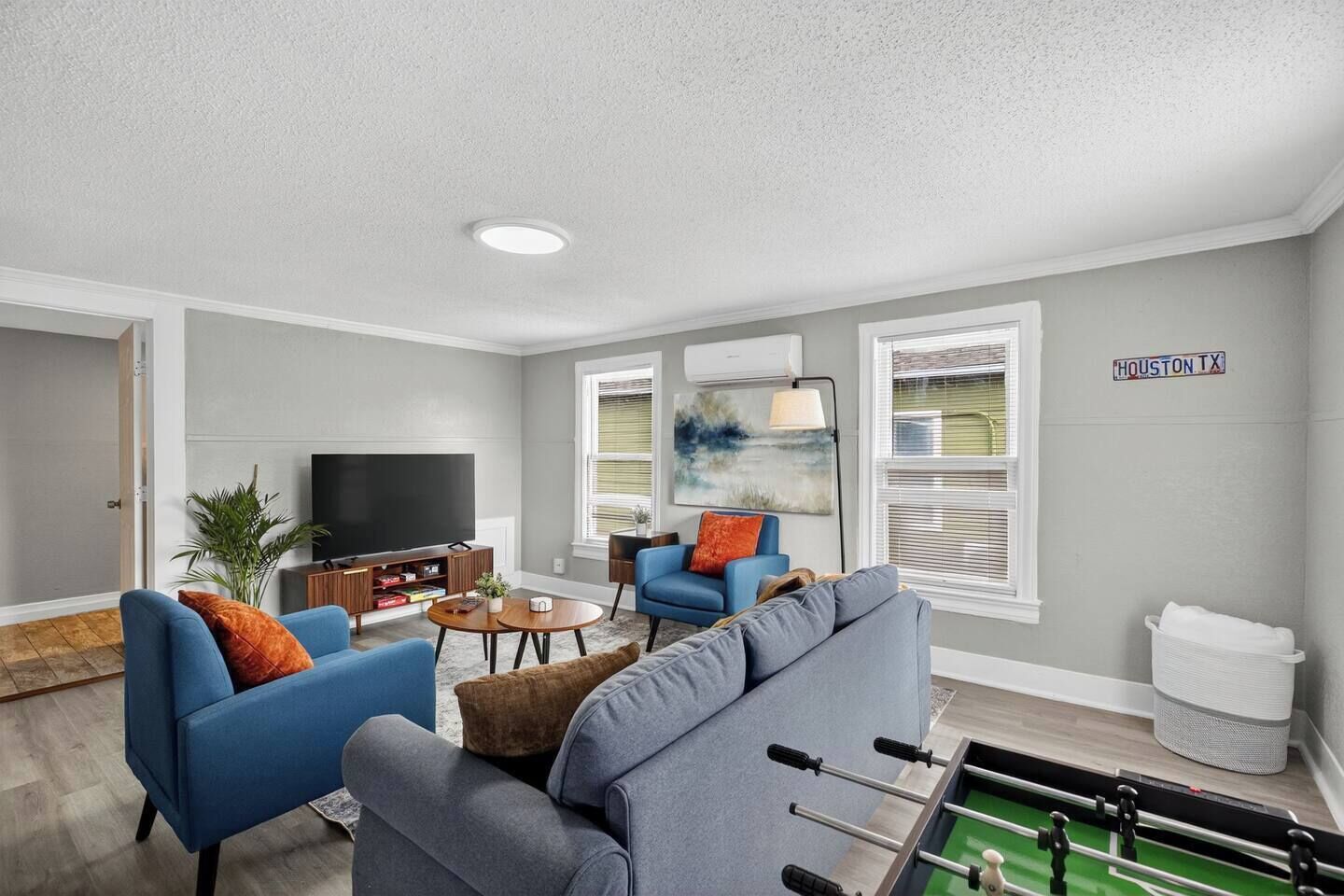 A living room with a television, sofas, a coffee table, and a foosball table.