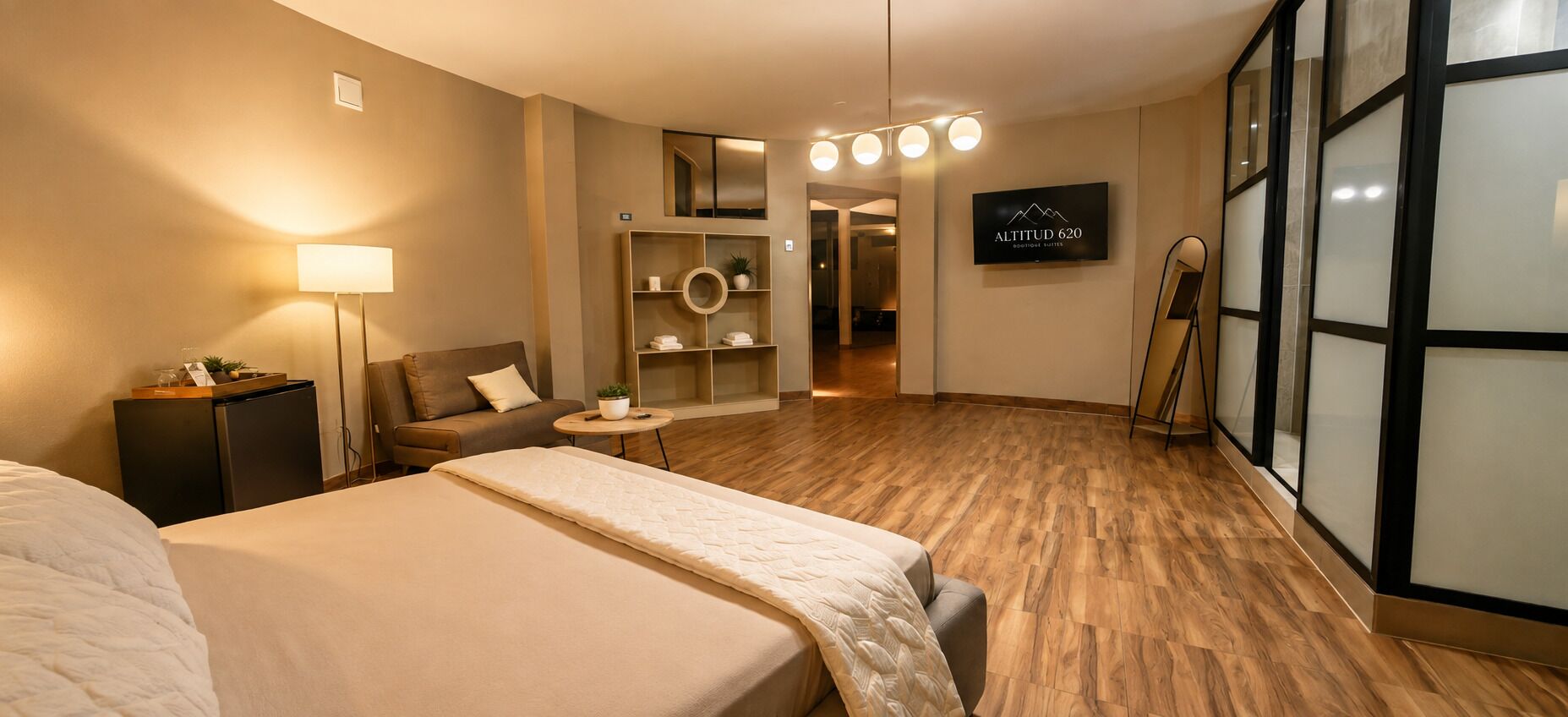 A hotel room with a bed, a sofa, a small table, a lamp, a TV, and a mirror.
