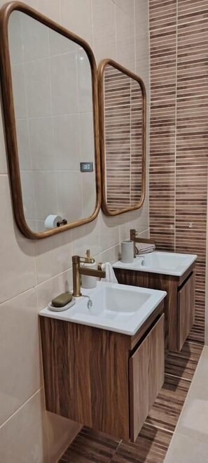 Un baño con dos lavamanos, muebles de madera y dos espejos.