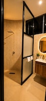 Un baño moderno con ducha, tocador con espejo y perchero para toallas.