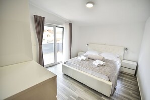 A modern bedroom with a large bed, a nightstand, a bedside table, and a sliding glass door leading to a balcony. - Charming 2-bedroom Apartment With Stunning Views in Vir (Vir)