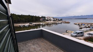 Un balcon avec vue sur une marina, des bateaux et des maisons de l’autre côté de l’eau.
