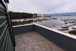 A balcony with a view of a marina, boats, and houses across the water.