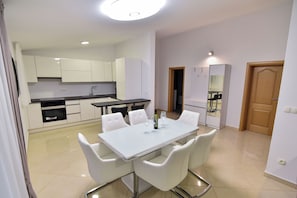 A modern kitchen with white cabinets, a dining table with chairs, and a large mirror. - Charming 2-bedroom Apartment With Stunning Views in Vir (Vir)
