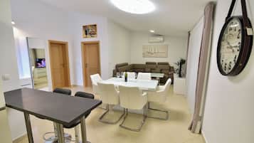 Un área de comedor con una mesa y sillas, un sofá y un reloj en la pared.