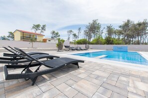 A pool area with lounge chairs and a small building in the background. - Charming 2-bedroom Apartment With Stunning Views in Vir (Vir)