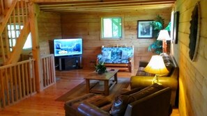 En inredning med träpanel, ett tv-appar, en soffa och ett bord.