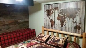 Une pièce avec un lit, un canapé à carreaux rouges et une grande carte du monde peinte sur le mur.