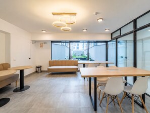 Un espace de bureau moderne, doté d’un canapé, de tables rondes et d’une grande fenêtre donnant sur la rue.