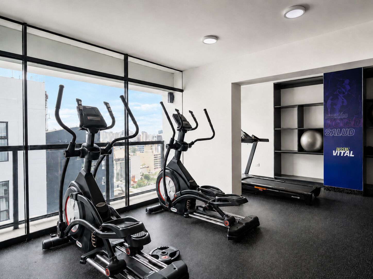 Une salle de sport équipée de deux appareils elliptiques, d’un tapis de course et d’un mur orné d’une affiche motivante.