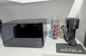 Eine schwarze LG-Mikrowelle, eine Nespresso-Kaffeemaschine und eine Unterlage mit Kaffeemotiv auf einer Arbeitsplatte.