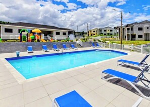 A swimming pool with lounge chairs and a children's play area.