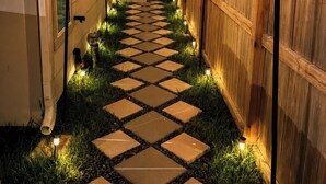 A narrow pathway with stepping stones and string lights, flanked by wooden fences and a building. - Luxury 1BR Private Suite • Private Entry • Houston Getaway (Houston)