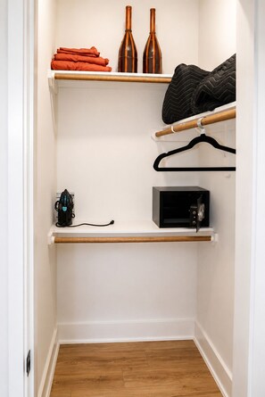 Ein Schrank mit Regalen, einem Kleiderhaken und einer Mikrowelle.