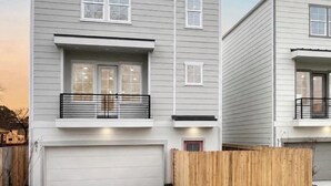 A two-story residential building with a garage, a balcony, and a wooden fence. - Luxury 1BR Private Suite • Private Entry • Houston Getaway (Houston)