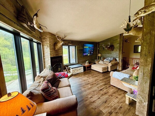 A rustic living room with wooden floors, a fireplace, and mounted animal heads.
