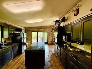 A kitchen with a central island, wooden cabinets, and a view to the outside.