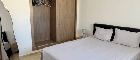 Quarto com cama, guarda-roupa e espelho.
