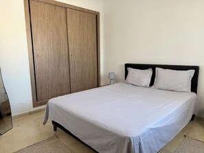 A bedroom with a bed, a wardrobe, and a nightstand. - Stylish 2BR Fully Equipped La Marsa (La Marsa)