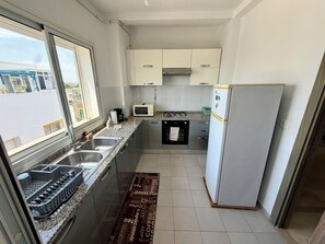 A compact kitchen with a microwave, stove, sink, and refrigerator. - Stylish 2BR Fully Equipped La Marsa (La Marsa)