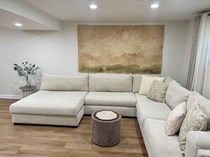 A modern living room with a sectional sofa, a round wooden coffee table, and a wall-mounted painting. - Charming 2-bedroom apartment in Alsip, full amenities workspace (Alsip)