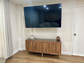 A room with a wooden cabinet, a flat-screen TV mounted on the wall, and a door.