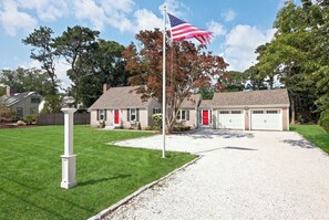 Ein Wohnhaus mit gepflegtem Rasen, einem Fahnenmast mit der US-amerikanischen Flagge, einer Garage mit zwei Toren und einer Haustür in Rot.