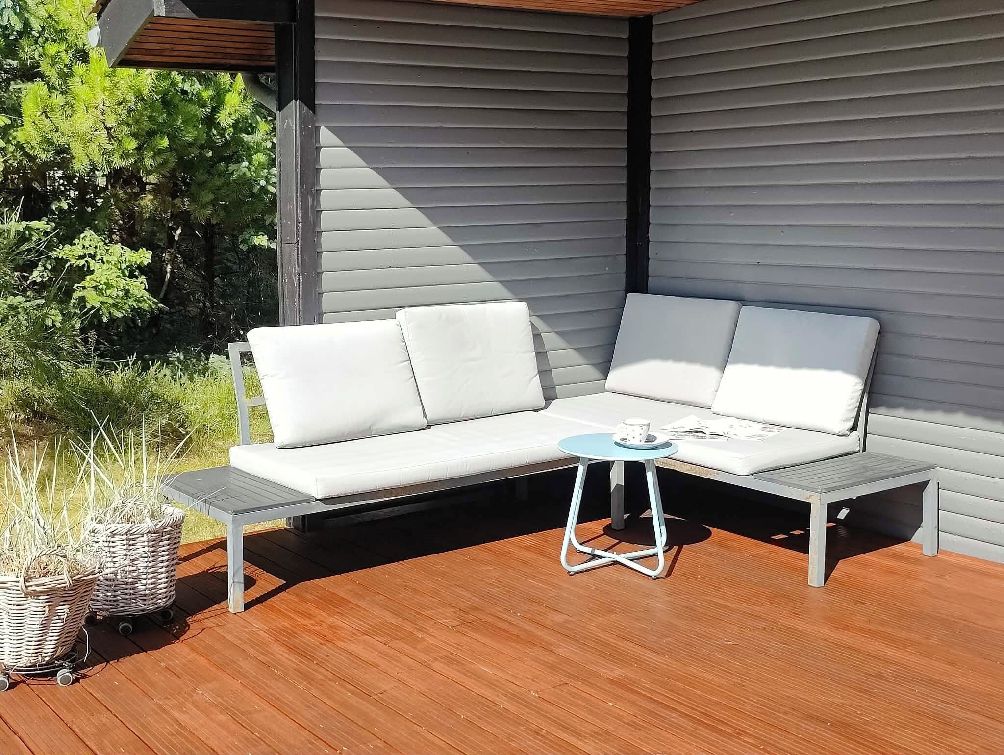 A corner outdoor seating area with a white sofa and a small round table.