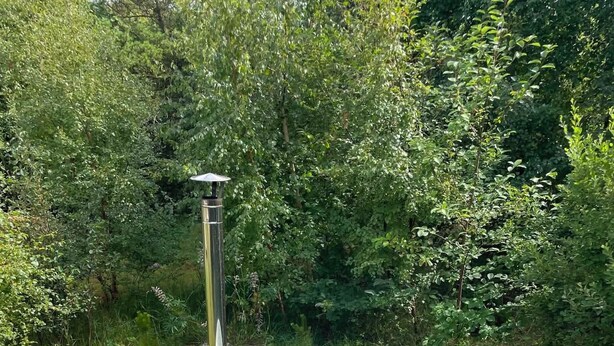 A hot tub in a garden with a wooden chair and a metal heater. - Cozy holiday home in Hune near Blokhus (Hune)