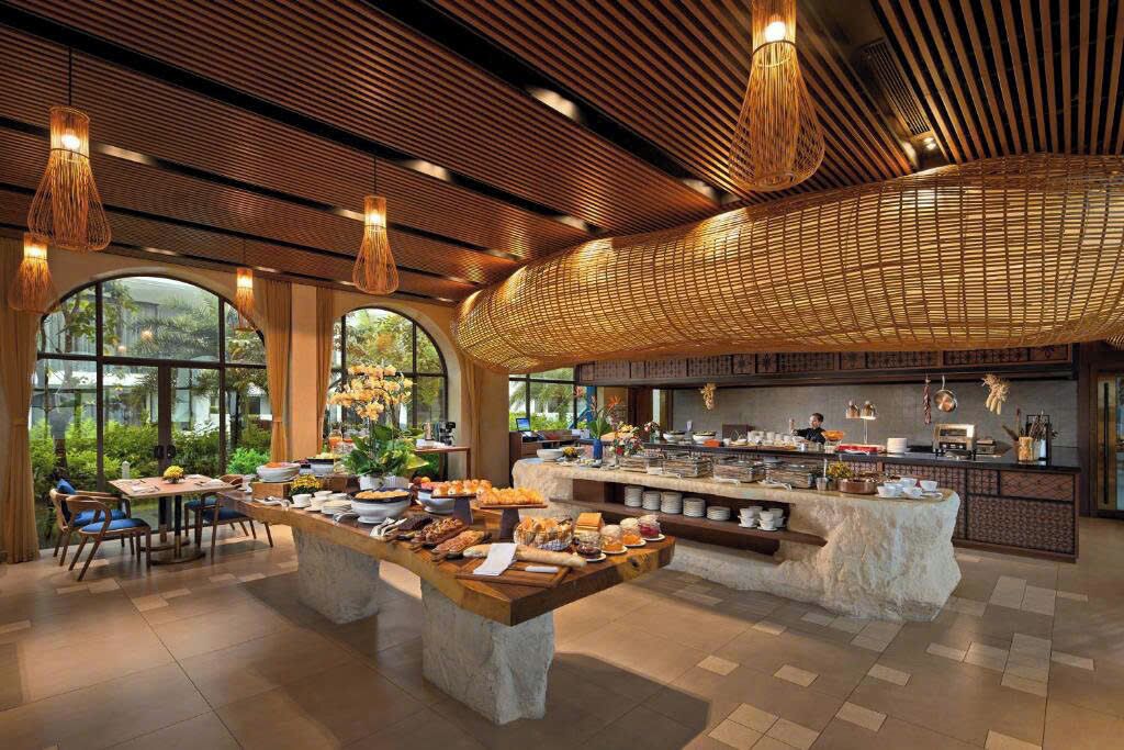 A spacious dining area with a buffet setup, large windows, and a modern ceiling design.