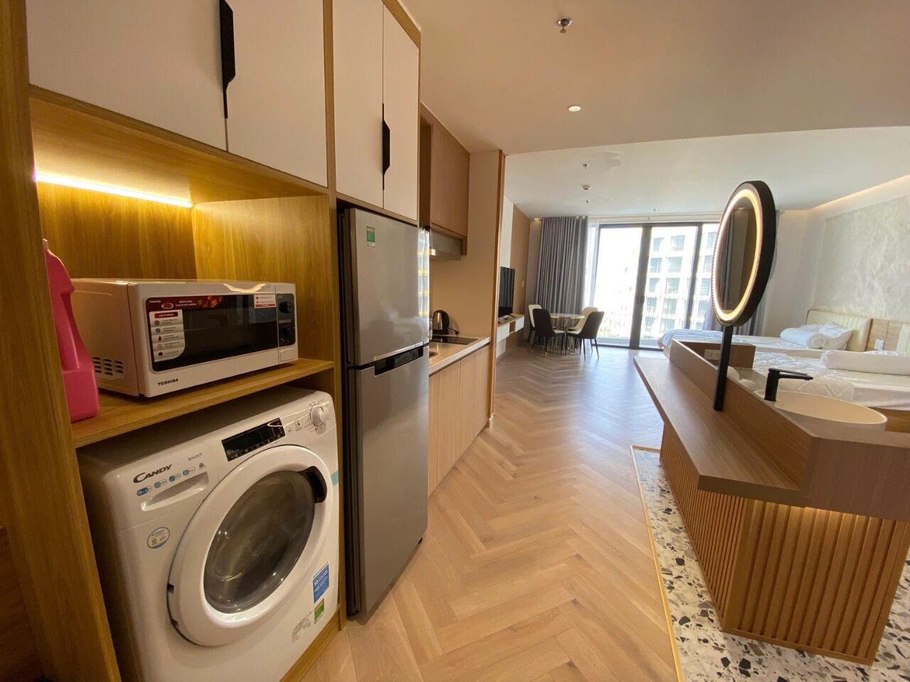 A modern kitchen with a washing machine, microwave, and refrigerator.