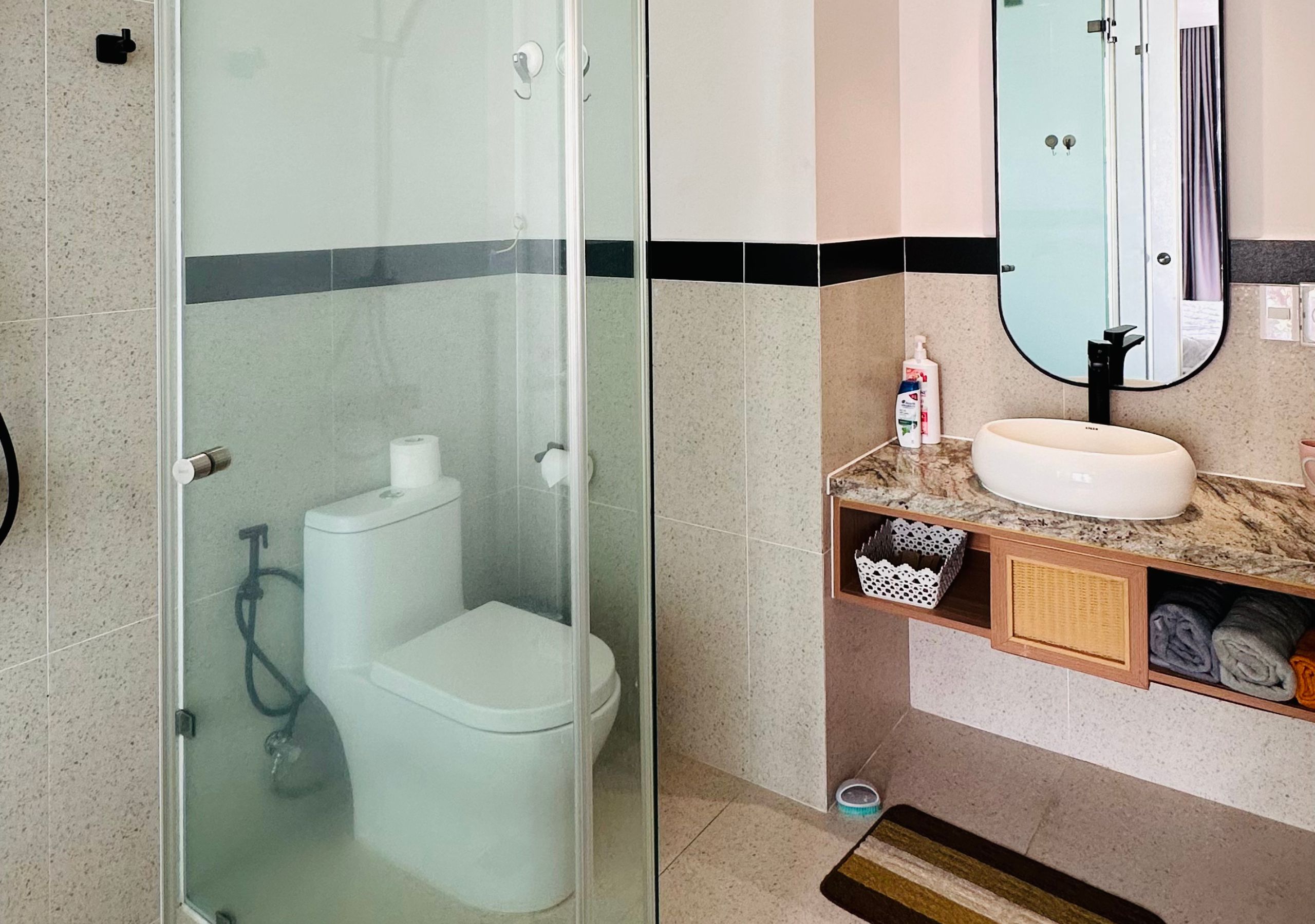 Une salle de bain avec une douche à parois de verre, des toilettes, un lavabo et un miroir.