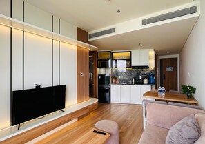 Una sala de estar moderna con un televisor de pantalla plana, piso de madera y un sofá.