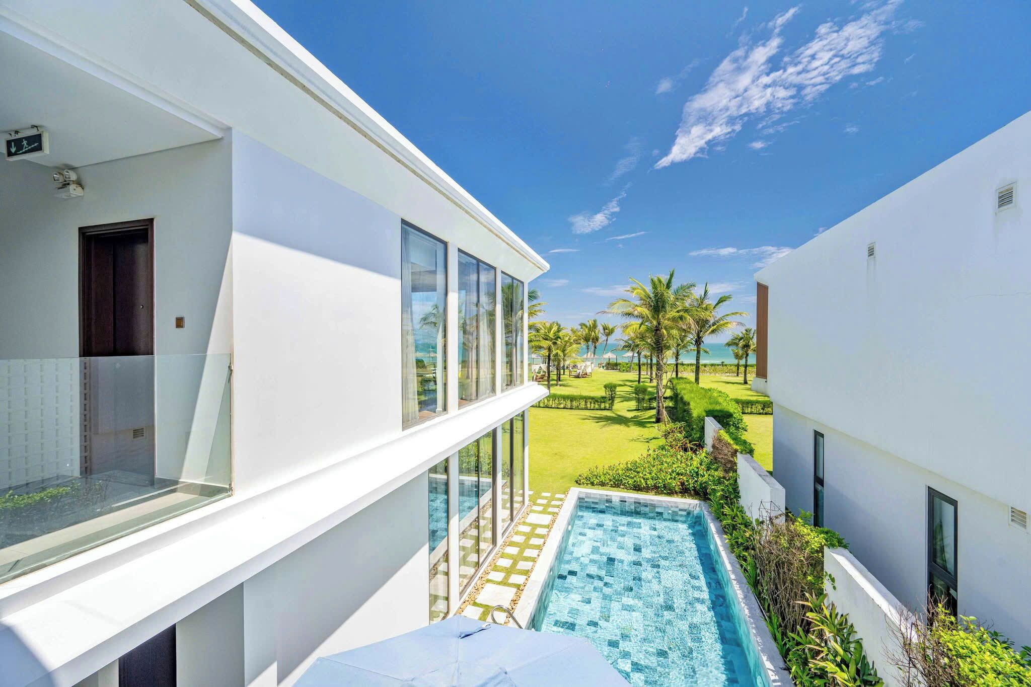 Un hotel moderno con piscina, vistas despejadas al océano y un césped bien cuidado.