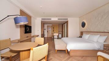 Une chambre d’hôtel comprenant un lit, un bureau avec des chaises, une lampe et un luminaire fixé au mur.