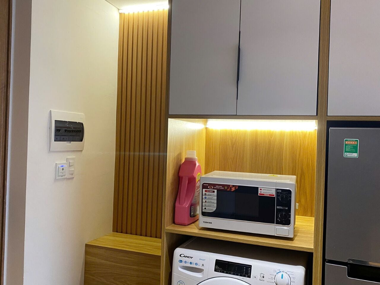 Eine kompakte Küchenzeile mit Mikrowelle, kleinem Kühlschrank und Waschmaschine.