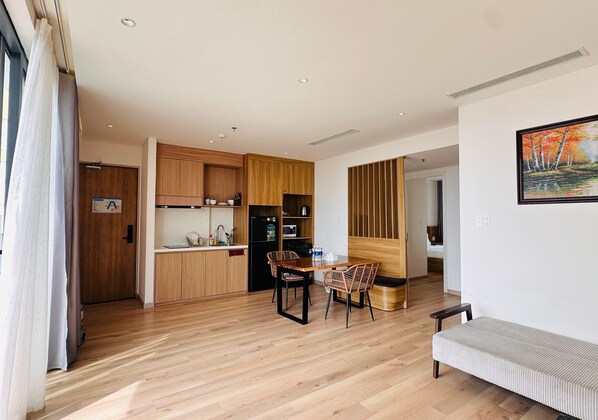 Una cocina moderna con armarios de madera, un comedor con mesa y sillas, y un cuadro en la pared.