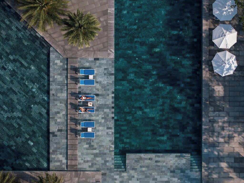 An aerial view of a pool area with lounge chairs and umbrellas.