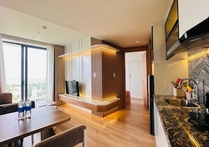 A modern kitchen with a built-in stove, a dining area with a table and chairs, and a large window providing a view of the outdoors. - Hoi An Sea Breeze Resort (Hoi An)