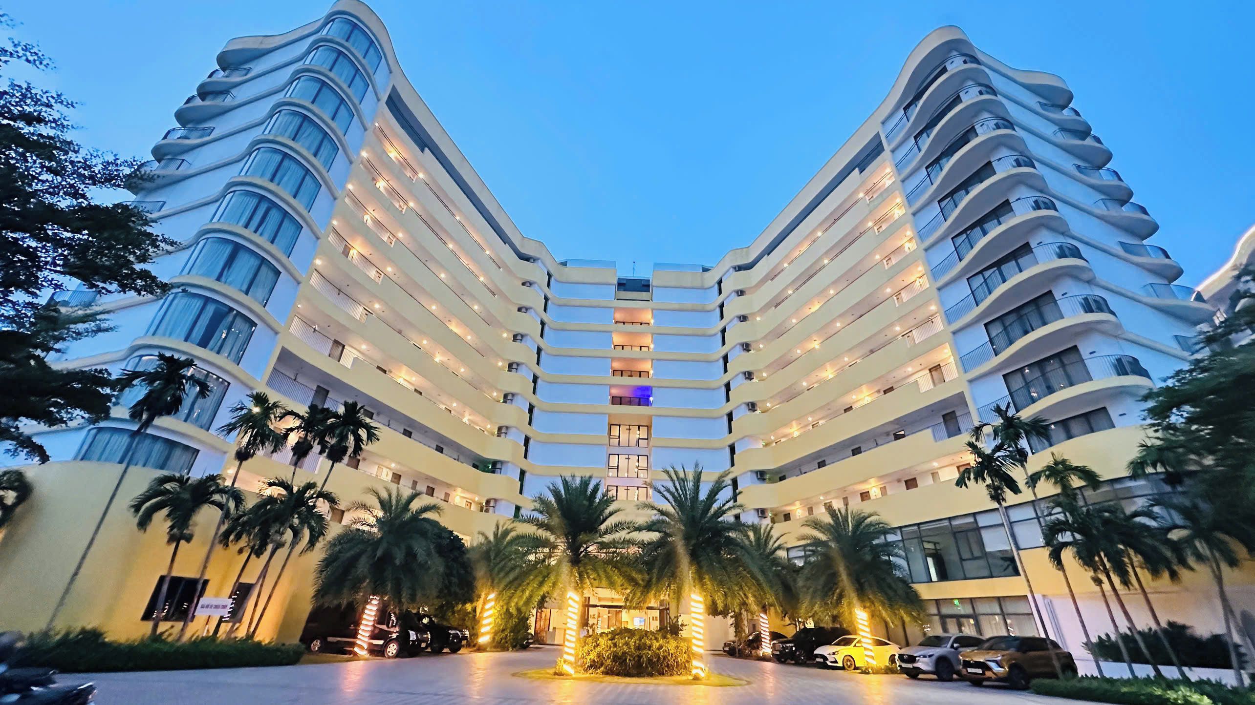 Un hôtel à plusieurs étages, doté d’une façade incurvée, de balcons et d’un atrium central.