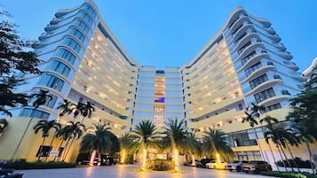 Un hôtel à plusieurs étages, doté d’une façade incurvée, de balcons et d’un atrium central.