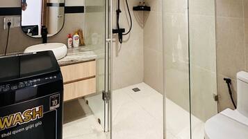 Un baño moderno con cabina de ducha de vidrio, inodoro blanco y lavabo con espejo arriba.