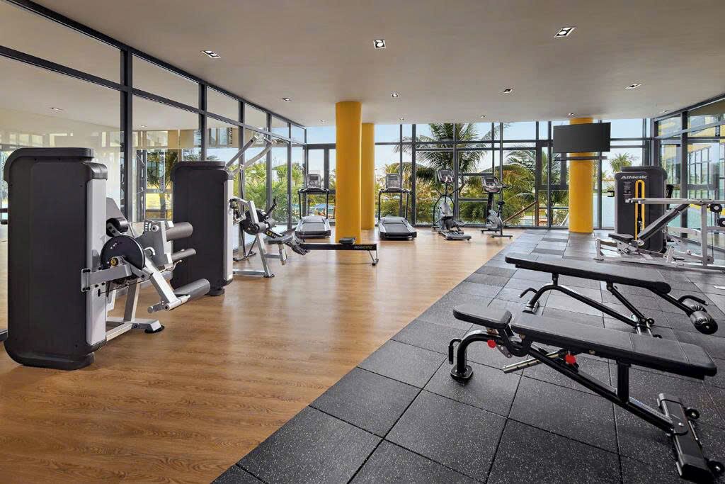 Een fitnessruimte met cardio-apparatuur, krachtstations en banken.