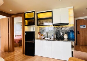 Una cocina compacta con electrodomésticos integrados, protector de salpicadero de mármol y una puerta de madera que da a un dormitorio.