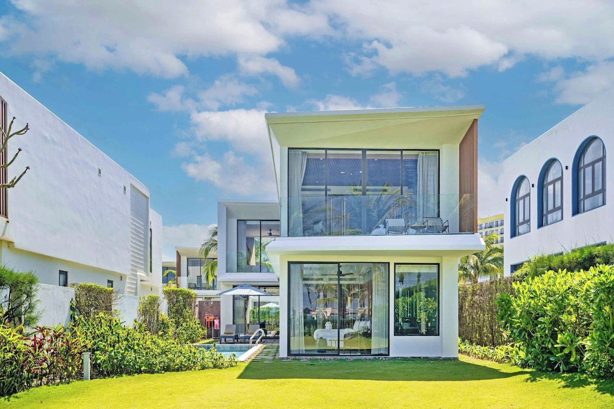 A modern two-story house with a large glass front, a swimming pool, and a well-maintained garden.
