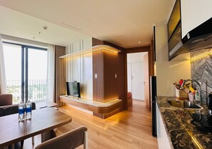 A modern kitchen with a built-in stove, a dining area with a table and chairs, and a large window providing a view of the outdoors. - Hoi An Sea Breeze Resort (Hoi An)