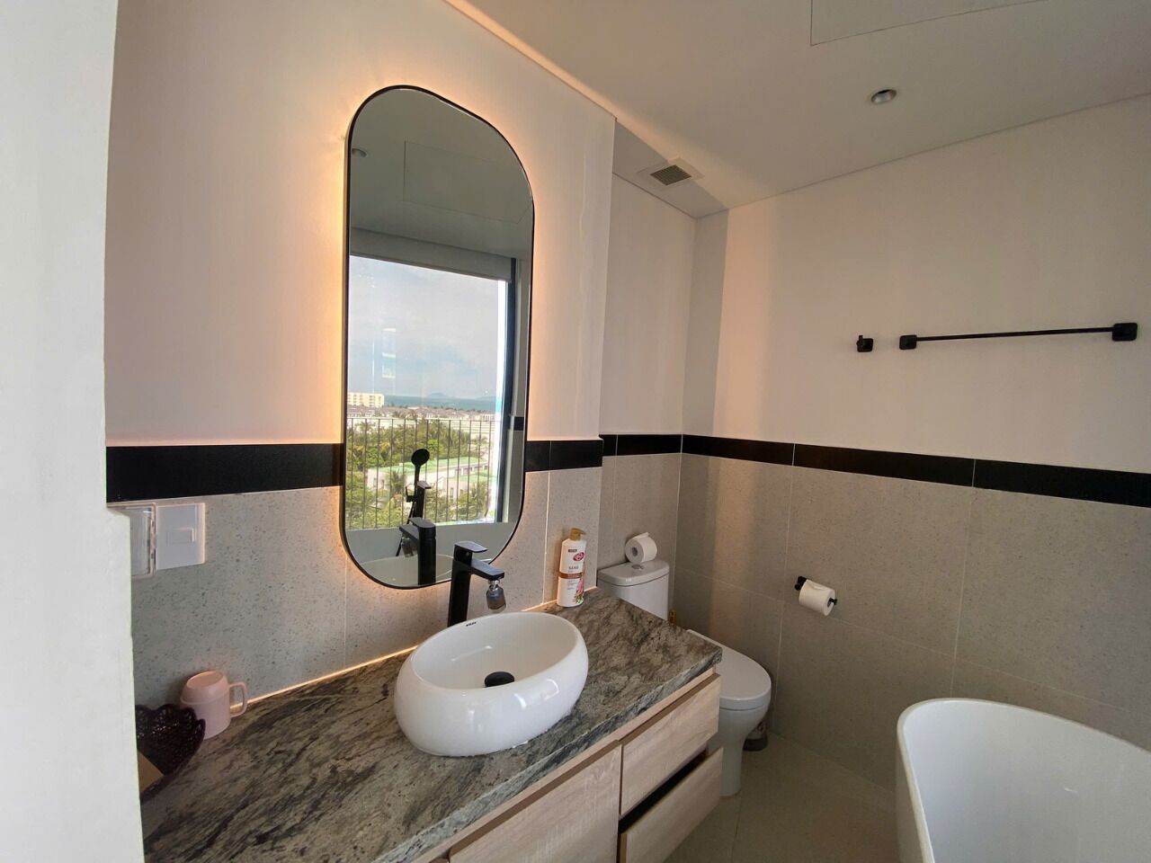A bathroom with a round sink, a mirror, a toilet, and a bathtub.
