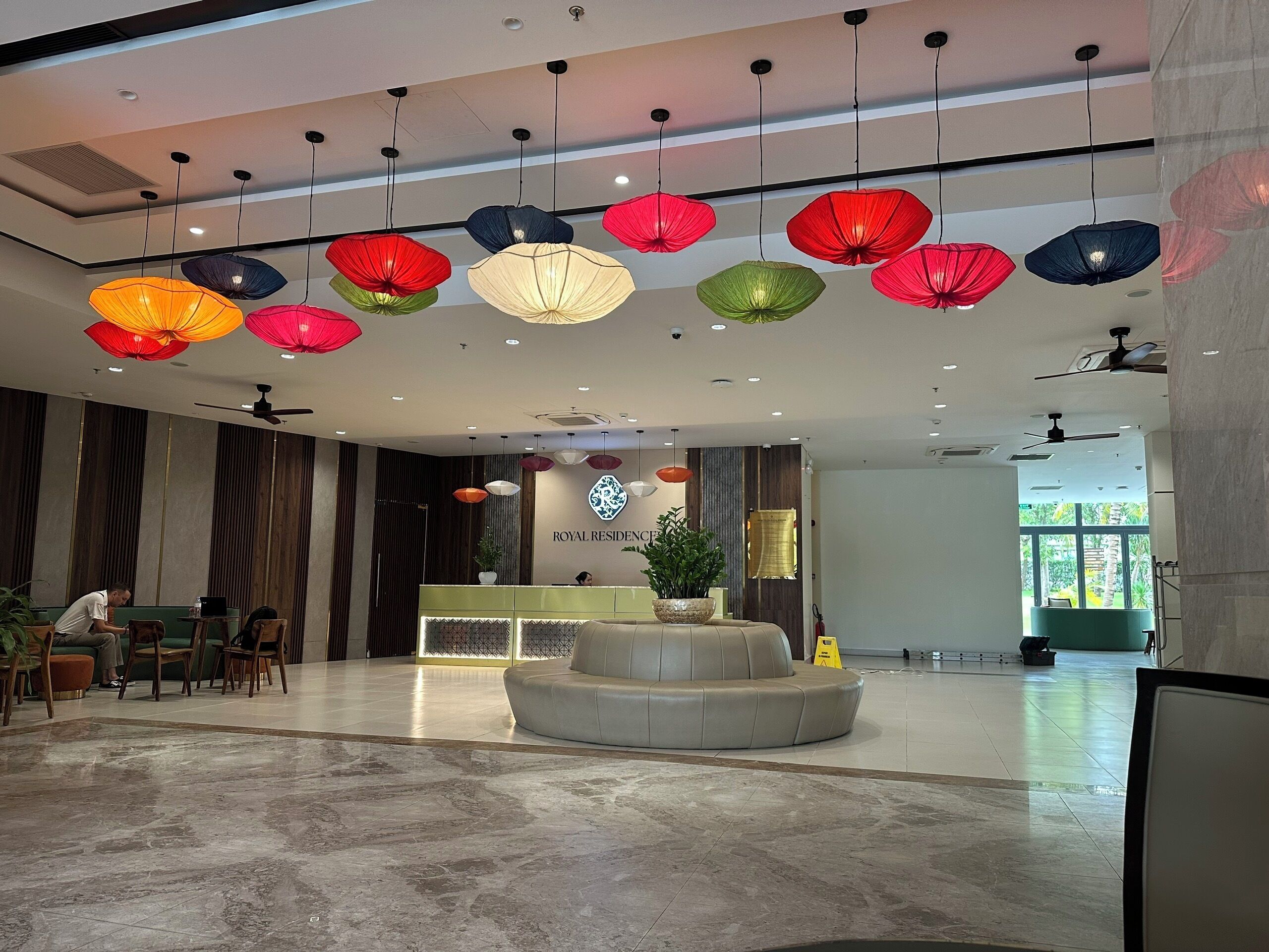 Un vestíbulo de hotel con recepción, zona de estar y un elemento decorativo central.