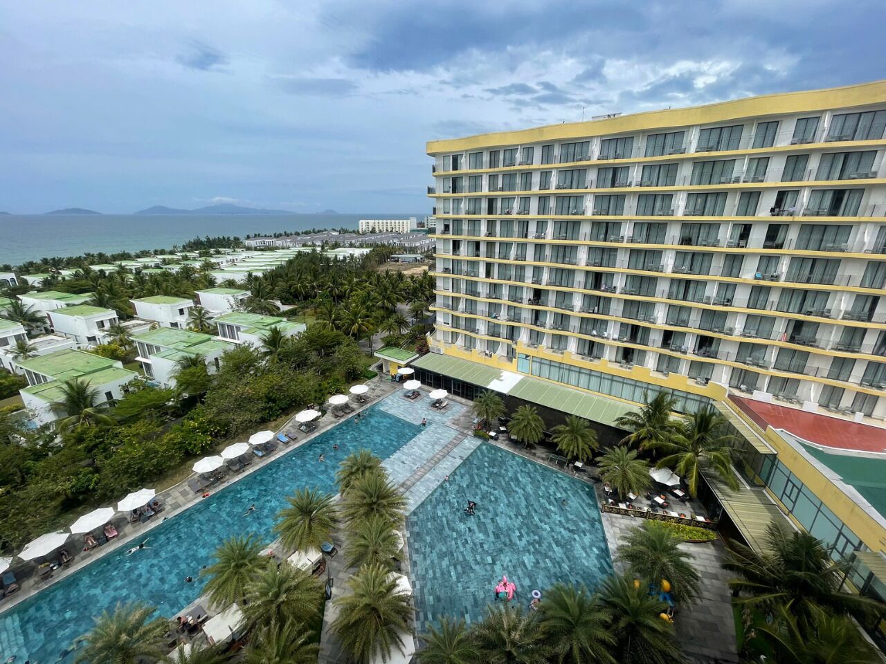 Um hotel com vários andares, piscina e vista para o mar.