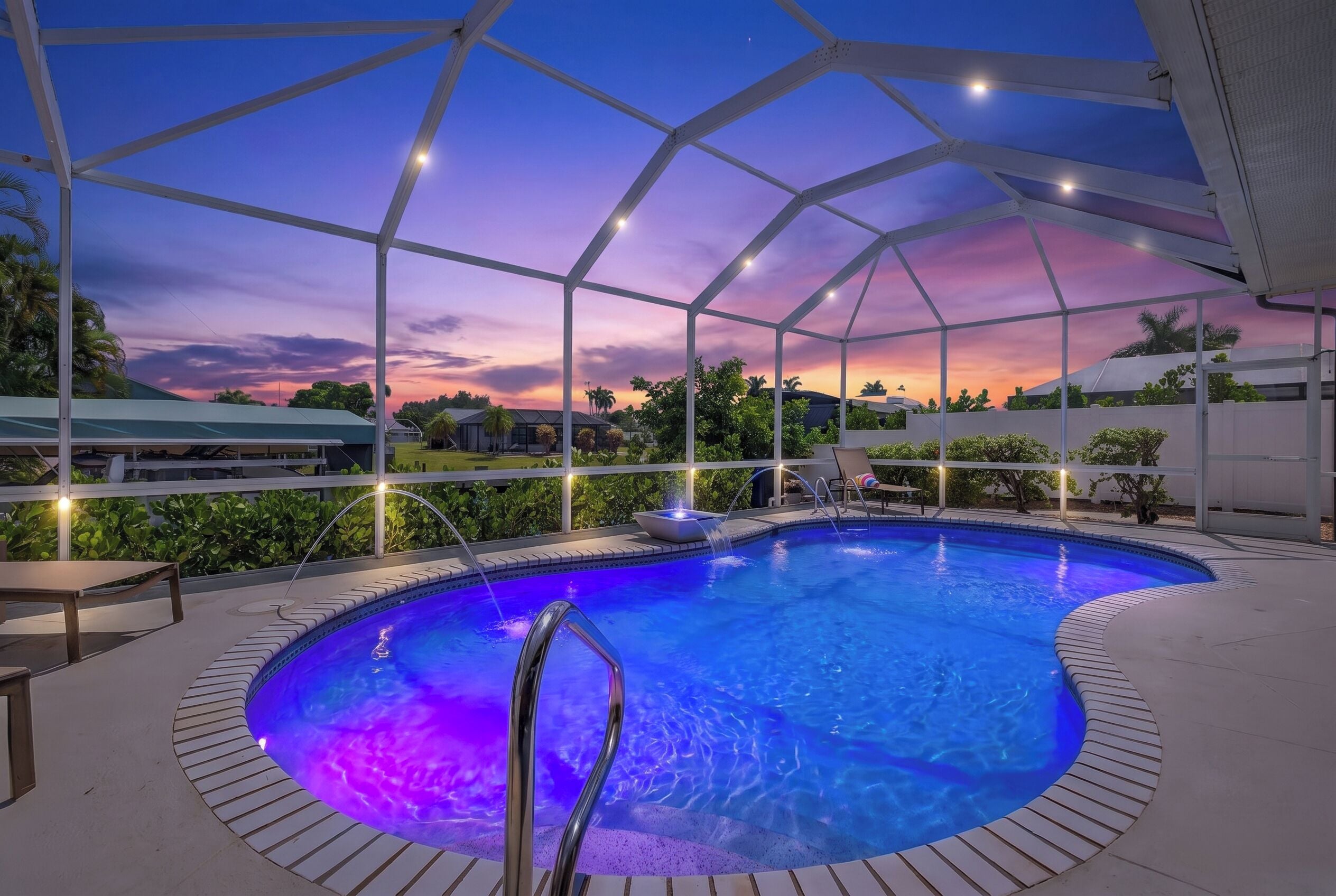 An indoor swimming pool with a view of the sunset and surrounding greenery.